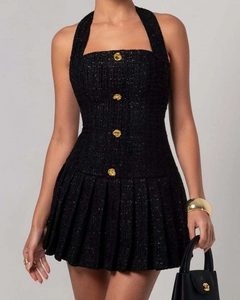 Makro-Detail der schwarzen Tweed-Struktur und geprägten Goldknöpfe am Neckholder-Kleid