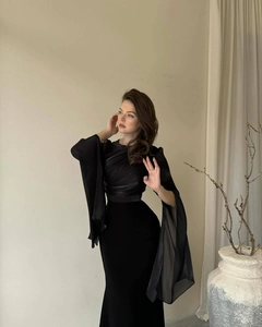 Detail of elegant black slim-fit evening dress featuring sheer batwing cape sleeves