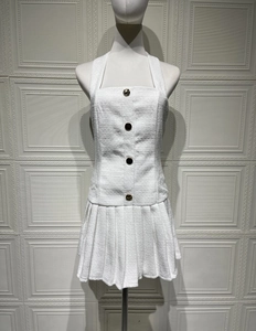 Detail eines weißen Tweed-Neckholderkleids mit strukturiertem Stoff und Zierknöpfen