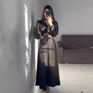 Détail d'une robe en satin noir avec poignets à volants et col montant élégant