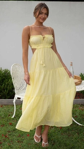 Detail of light yellow sleeveless dress showing waist cut-outs and ruffled tiered hemline