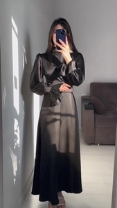 Selfie miroir d'une robe longue en satin noir avec manches longues et poignets à volants