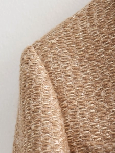 Macro shot of tweed jacket texture with woven gold threads and tiny sequins