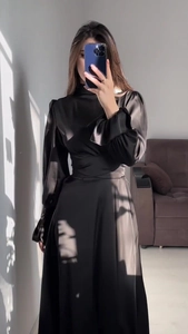 Détail d'une robe en satin noir brillant montrant la taille plissée et les manches bouffantes