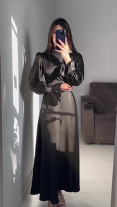 Détail macro d'une robe en satin noir élégante avec poignets à volants et texture soyeuse