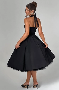 Detailed back view of black halter dress featuring a large bow and layered puffy skirt