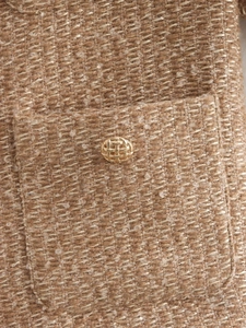 Macro shot of tweed fabric texture with shimmering sequins and gold woven metal button