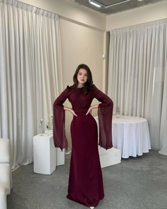 Detail of burgundy evening gown featuring long sheer bell sleeves and slim-fit fishtail cut
