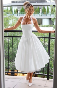 Detail of elegant white halter neck dress with pleated voluminous skirt and fitted waistline