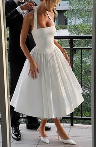 Detail of white halter neck dress featuring a pleated skirt and elegant low-back design