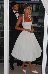 Detail of elegant white halter neck dress with tied back ribbon and large pleated skirt