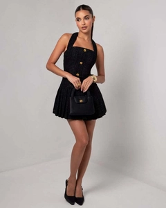Detailaufnahme des Tweed-Halter-Minikleides mit geprägten Goldknöpfen und Faltenrock