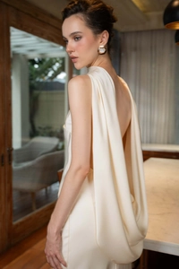Détail d'une robe de soirée dos nu en satin avec un drapé fluide et des boucles d'oreilles