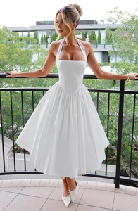 Detail of white halter neck dress featuring a square neckline and pleated A-line skirt