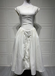 Detailed view of white satin midi dress featuring a smooth texture and elegant pleated hem