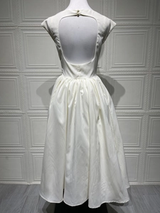 Detailed back view of white sleeveless open back dress with pearl button and pleats