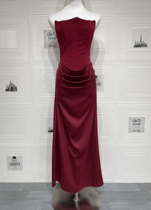 Detail of burgundy off-shoulder evening dress featuring elegant waist pleats and long drape