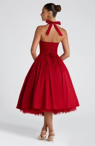 Detail of red halter dress featuring a corset lace-up back and large satin neck bow