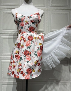 Detail of white floral satin dress with red roses, lace trim, and inner tulle petticoat