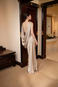 Détail d'une robe de soirée élégante en satin champagne avec un dos nu drapé et une coupe longue