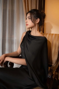 Détails de la texture satinée noire et du drapé asymétrique à une épaule sur la robe