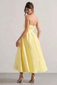 Détail d'une robe bustier jaune évasée avec jupe plissée et taille cintrée ajustée