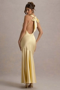 Back view of yellow satin mermaid dress featuring backless design and large bow detail