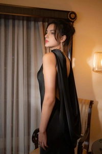 Détail d'une élégante robe de soirée en satin noir avec dos nu et drapé effet cape chic