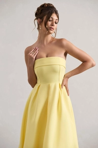 Détail de la robe bustier jaune pâle avec plis élégants à la taille et tissu de haute qualité
