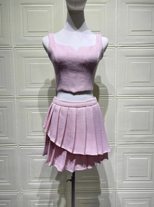 Detailed macro view of pink tweed fabric texture on a sleeveless crop top and pleated skirt