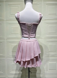 Detail of pink tweed two-piece set featuring lace-up back crop top and pleated mini skirt