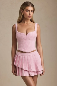 Detail of pink tweed two-piece set featuring corset top and layered pleated mini skirt