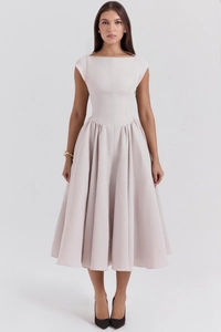 Detail of elegant beige A-line midi dress with wide pleated hem and boat neck design