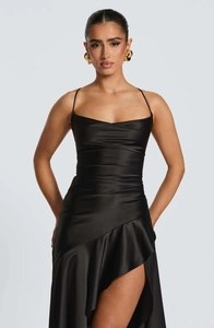 Detail view of black satin strap dress featuring ruffled hem and side slit design