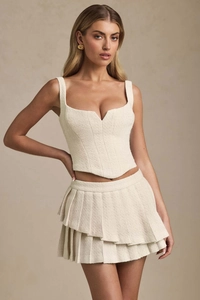 Detail of cream tweed two-piece set featuring notch neckline corset top and pleated skirt
