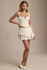 Close-up of elegant off-white tweed corset top and matching pleated mini skirt set