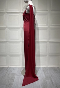 Detail of burgundy satin evening dress showing the high slit and side silhouette on a mannequin
