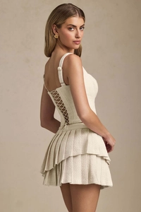 Detail of tweed crop top with criss-cross back lacing and pleated mini skirt set