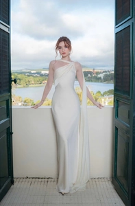 Detail of elegant white satin evening gown featuring one-shoulder draped neckline with sash