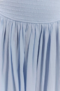 Vue détaillée de la texture smockée bleu clair et des plis élégants de la jupe longue