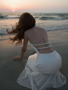 Detail of white satin backless maxi dress with double-layered luxury pearl chains on the back