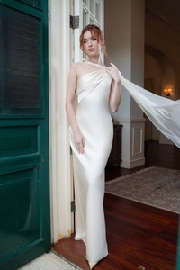 Detailed close-up of cream satin dress with elegant diagonal shoulder drape and ruched texture