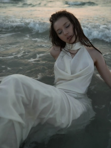 Detailed view of the white backless satin dress showing the draped neckline in sea water