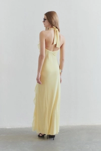 Detail of yellow backless halter dress with ruffled hem and flowy chiffon fabric