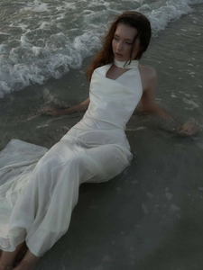 Detail of elegant white satin halter neck dress with silk texture and pleated neckline