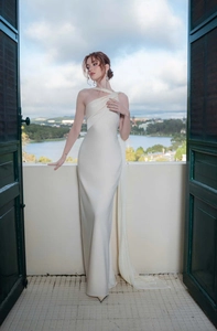 Detail of elegant ivory satin dress showing one-shoulder neckline and draped cross design
