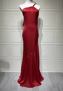 Detail of red satin evening gown featuring elegant pleats and a sleek fishtail silhouette