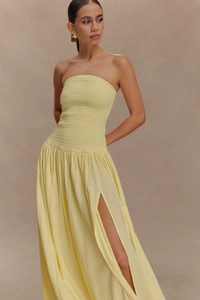 Détail d'une robe bustier smockée jaune clair avec fente haute et tissu à texture raffinée