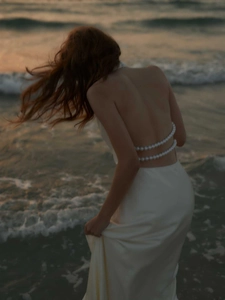 Close-up of elegant open back detail with luxury pearls on a white satin maxi dress