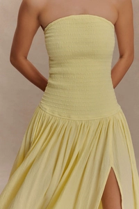Détail du bustier froncé sans bretelles et fente latérale haute sur une robe longue jaune